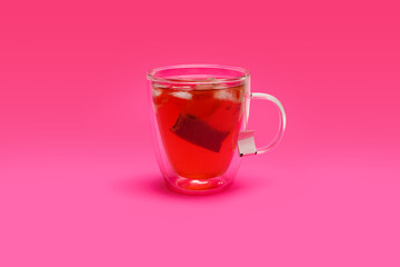 Red ice tea in a double-wall glass mug on a red background
