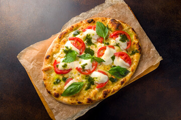 Italian pizza Margherita buffalo with tomatoes, mozzarella and basil on brown concrete table top...