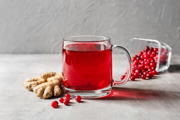 Cup of tasty lingonberry tea and ginger on table
