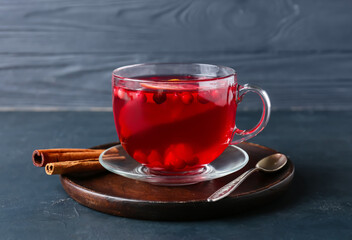 Glass cup of tasty lingonberry tea and cinnamon on table