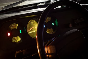 Foto op Canvas The close up view of an illuminated dashboard of a retro vintage AZLK 2140 car with focus on the speedometer and all the signal lights turned on in the night with copy space © J S