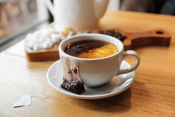 Cup with tea bag and lemon on table in cafe, closeup