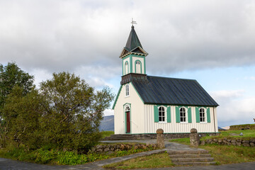 Fototapeta na wymiar Thingvellir church in Thingvellier Park in Iceland. Cloudy sky with areas of blue. Side angle of church.