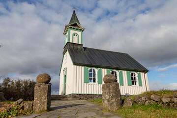 Fototapeta premium Thingvellir church in Thingvellier Park in Iceland. Cloudy sky with areas of blue. Side angle of church.