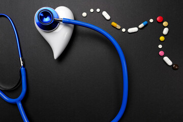 medical stethoscope, many colored pills, pills, capsules with medicine on a black background, the concept of maintaining health, medication treatment, vitamins, dietary supplements, top view