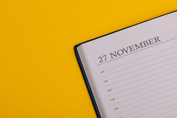 Notepad or diary with the exact date on a yellow background. Calendar for November 27 - autumn time. Space for text.