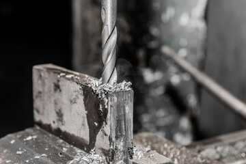 Thick drill drilling old iron bar, steel work equipment close-up
