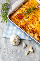 Potato gratin - graten (baked potatoes with cream and cheese) with rosemary and forks (Turkish name; Kremali patates)