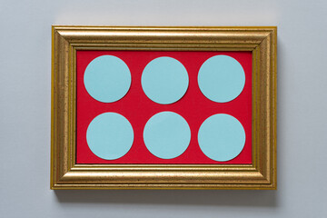 gold frame with red paper and blue circles on gray paper