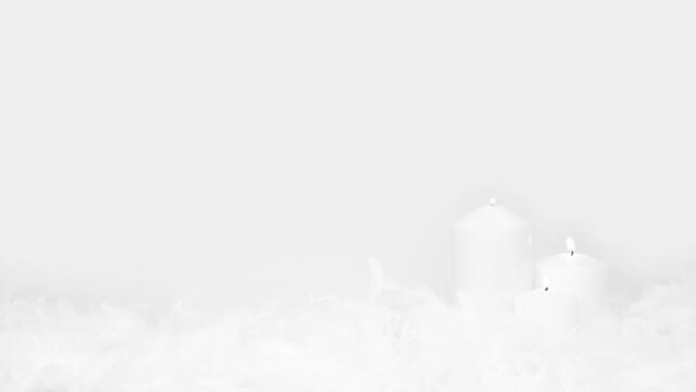 Magical setting. White candles are burning among the feathers isolated on a white background.