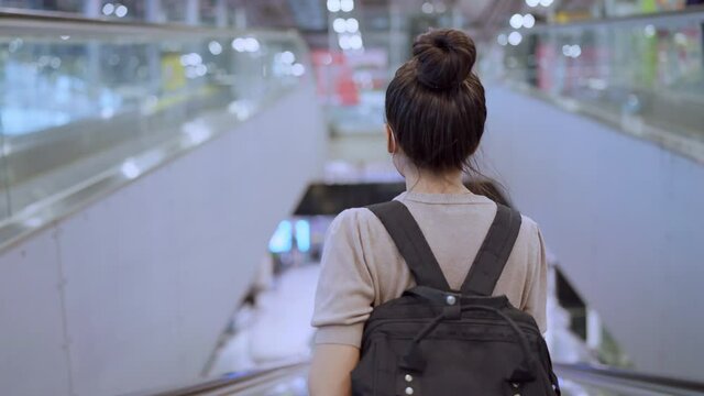 young attractive asian female traveller wearing face mask hand use smartphone checking map and flight schedule waking with luggage and handbag at airport terminal new normal travel lifestyle 