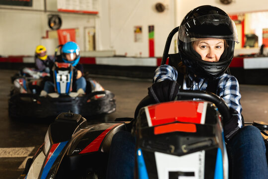 Portrait of happy woman driving racing car at kart circuit