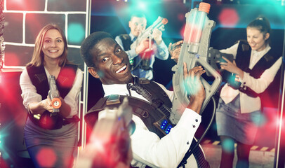 Portrait of African Americanbusinessman playing laser tag with his co-workers on dark gaming arena