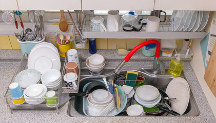 Plates stacked on the sink at home. a lot of washing up.