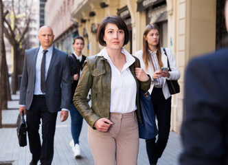 Hurrying business woman in casual wear fast walking on city street during peak hour
