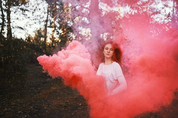 Smoke screen in the woods. Woman with smoke. Beautiful woman with pink smoke behind her in the...