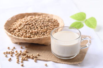 Soy milk in a cup glass and soy beans in a bamboo basket on white background, Healthy drink