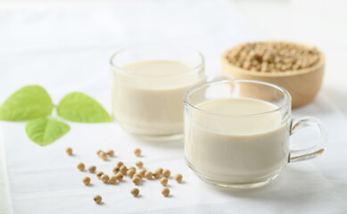 Obraz na płótnie Canvas Soy milk in a cup glass and soy beans in a bowl on white background, Healthy drink