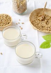 Soy milk in a cup glass and soy beans in a bamboo basket and bowl on white background, Healthy drink