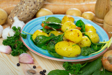 Scene with delicious boiled new potatoes with spinach decorated with garlic, onion and bread