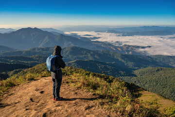 Man hiking looking at mountain range on the top of mountain in tropical forest, Outdoor adventure travel concept