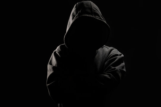 Man without a face in a hood on a dark background.