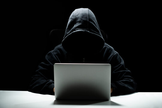 hacker in a hood on a dark background, IT specialist