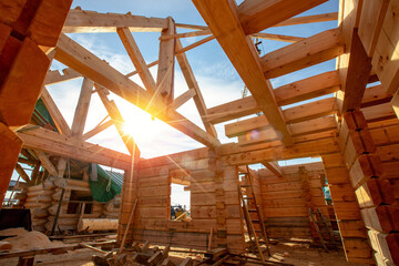 New house wooden log construction interior with exposed framing roof with sun light