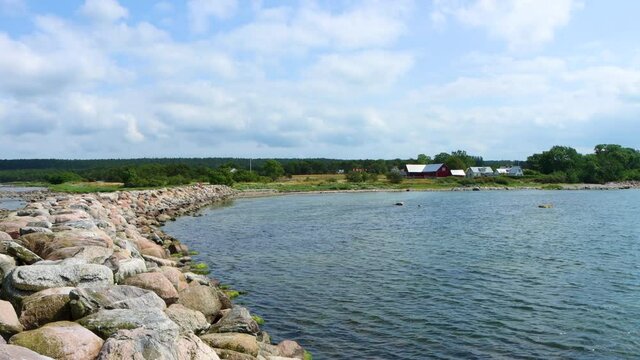 Peaceful view of water in bay by stony pier and green nature, Gotland