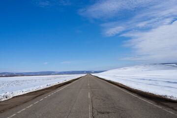 Asphalt road, highway. The road leaving into the distance, perspective. Winter rural landscape.