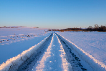 Winter road. Road track in deep snow. Winter evening landscape.