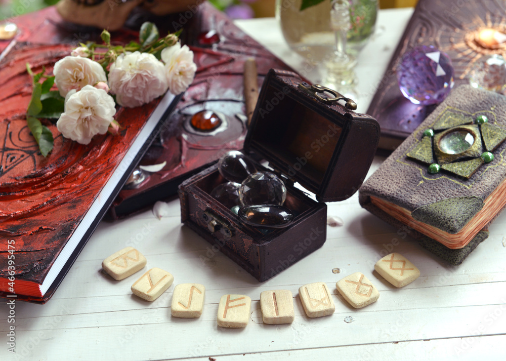 Wall mural vintage still life with old spell book, runes, roses and magic object on witch table.