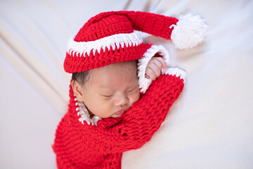 Cute Newborn baby wearing santa costume lying and sleep waiting for celebrate merry christmas and happy new year.Calm of infant baby sleep with red santa cloth