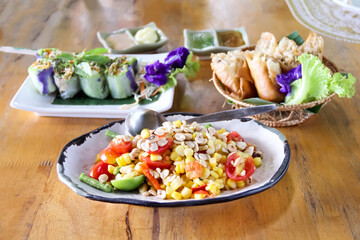 Corn spicy salad on white plate on wood table background