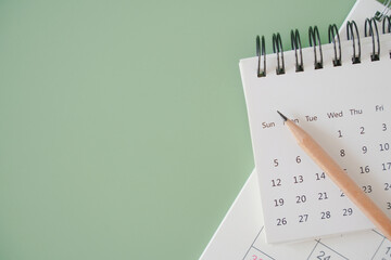 top view of white calendar and sharpen brown pencil on green background, schedule, timeline,...