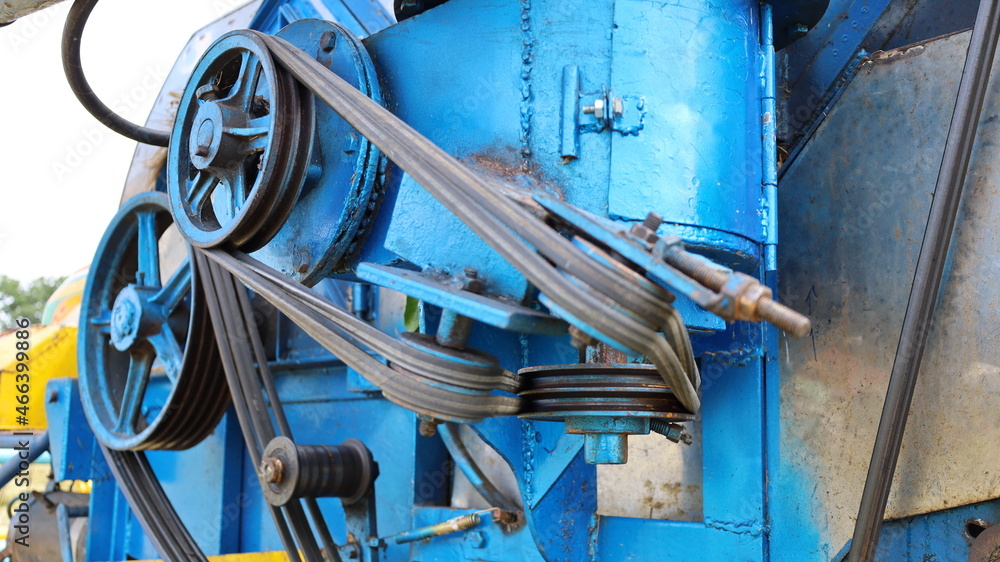 Wall mural Close up pulley and belt. Transmission belt with multiple pulleys on a blue combine harvester background. select focus on subject