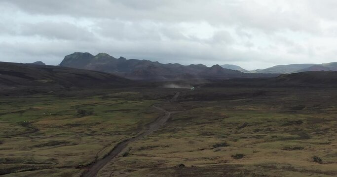 A bus moving towards the camera creating a dust cloud in a moody epic setting in the Highlands of Iceland