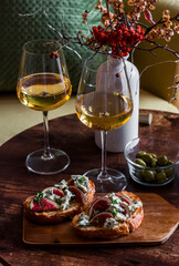 Two glasses of white wine and gorgonzola bruschetta figs in a cozy interior on a wooden table