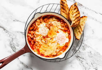 Tomato sauce beans, cheese, eggs baked shakshuka in a ceramic frying pan with a grill crispy bread...