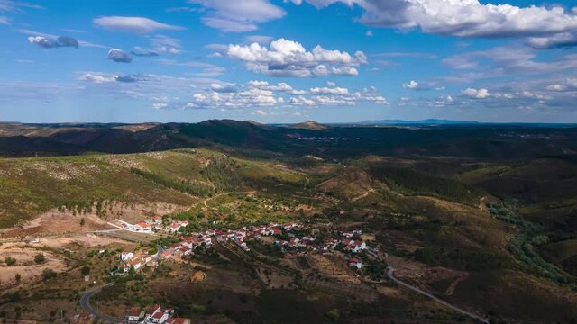 Aerial Hyperlapse over a small village surrounded by mountains. Beautiful blue sky and clouds landscape.
