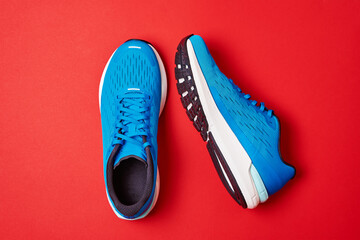 Blue running sneakers on red background. Pair of sport male shoes for fitness, top view