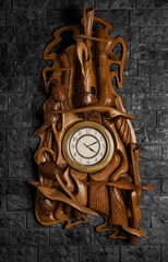 Wooden decorative and simple wall clock hanging on a black brick wall.