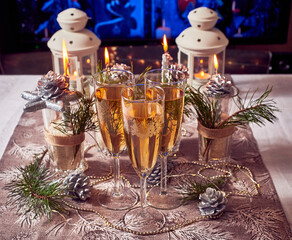 Silver candles, lights, cones, glasses of champagne, Christmas decorations on the table.