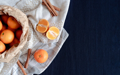 Mandarin oranges and cinnamon sticks on a blue textured background, with copy space, styled flat lay