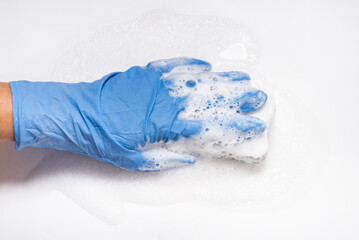Hand with foam holding sponge, cleaning white surface