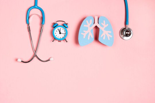 Prevention of pulmonary disease. Lung symbol, stethoscope and alarm clock on a pink background.