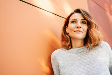 Serene young woman standing deep in thought looking up
