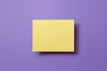 Blank yellow memo pad on purple background. top view, copy space