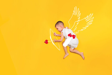 Happy toddler boy cupid in costume angel dress, wings, bows and hearts arrow isolated on yellow...