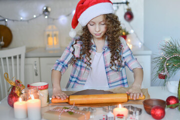 The girl is rolling out the dough for cristmas cookies. They are in the kitchen at home. Horizontal frame.